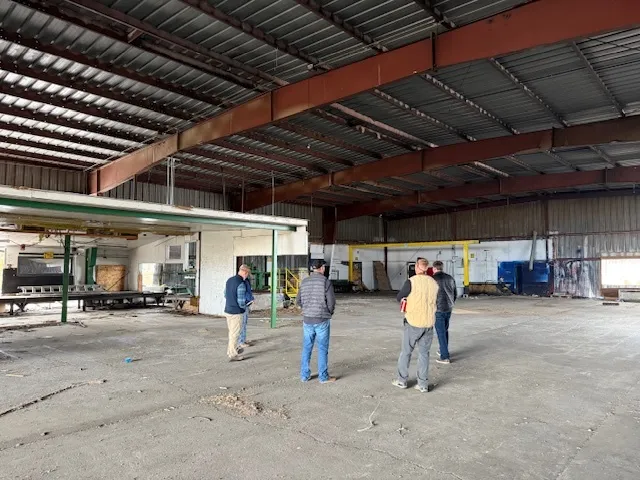 Inside a large hangar building on the campus, with a group walking the floor